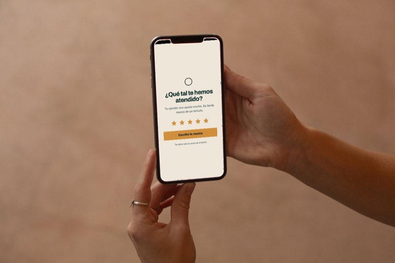 Unas manos sostienen un móvil con una pantalla para puntuar con estrellas y escribir una reseña.
